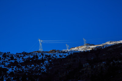 中国西藏地区雪山上的输电铁塔及电力线路