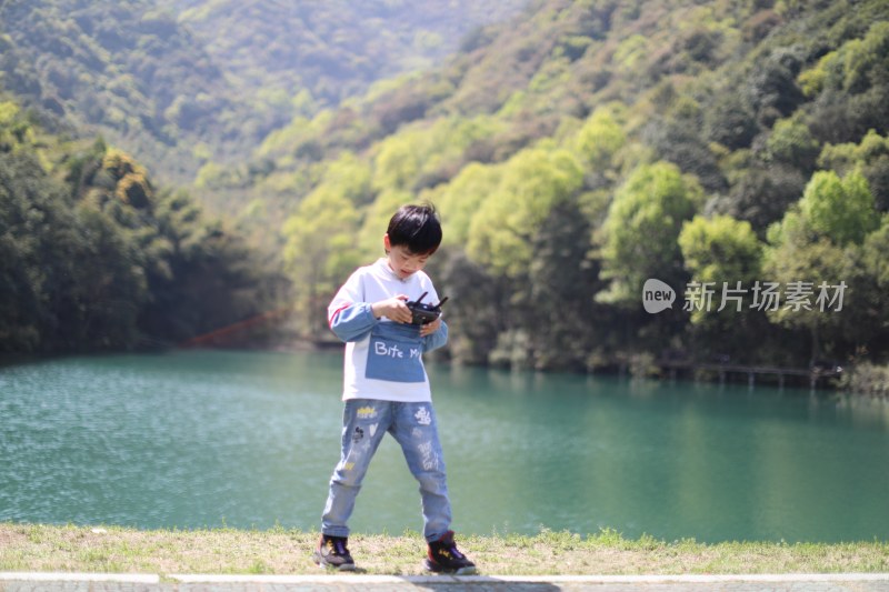 在湖边玩小飞机的中国小男孩