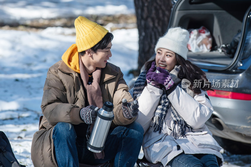 坐在汽车旁的青年夫妇