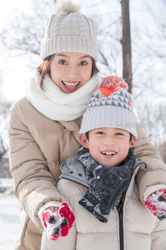 年轻妈妈带着孩子在雪地玩耍