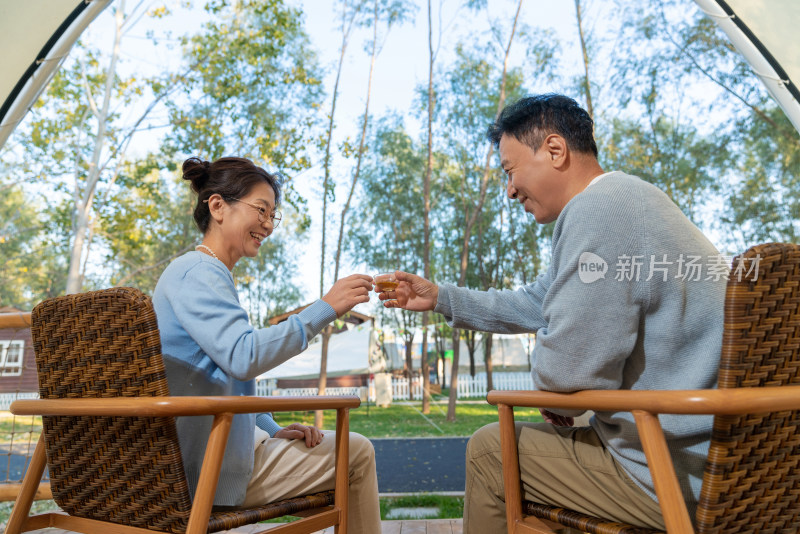 老年夫妻在露营地坐着摇椅喝茶聊天