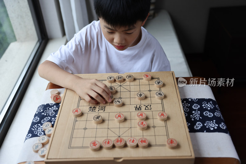 可爱的男孩在窗边下中国象棋