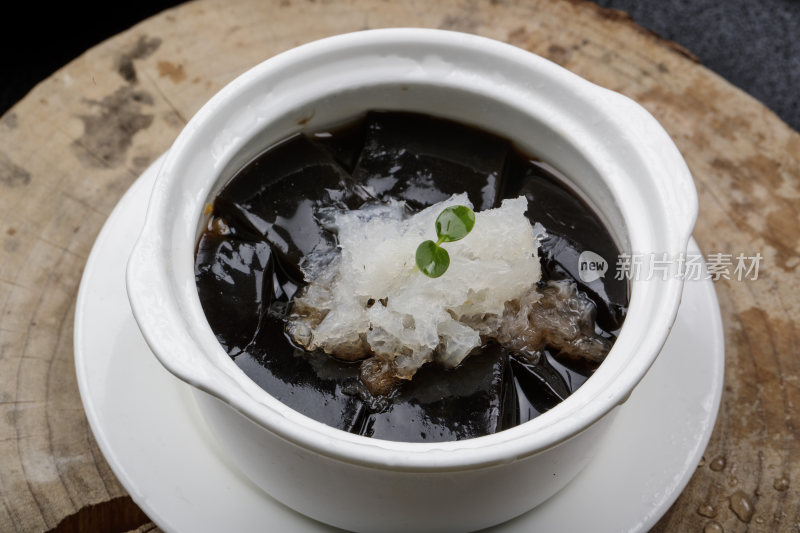 白色汤盅装的银耳龟苓膏摆放在樟木砧板上