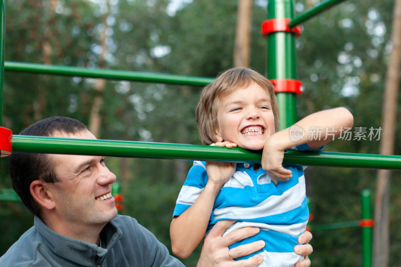 父亲与孩子在户外游乐设施互动