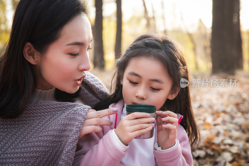 秋天户外幸福的母女在喝水