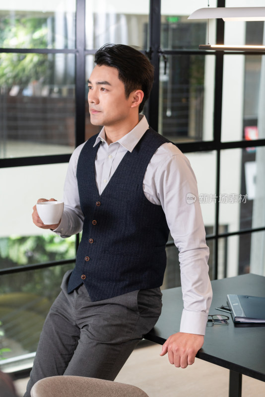 一个商务男士靠在会议桌前办公喝咖啡