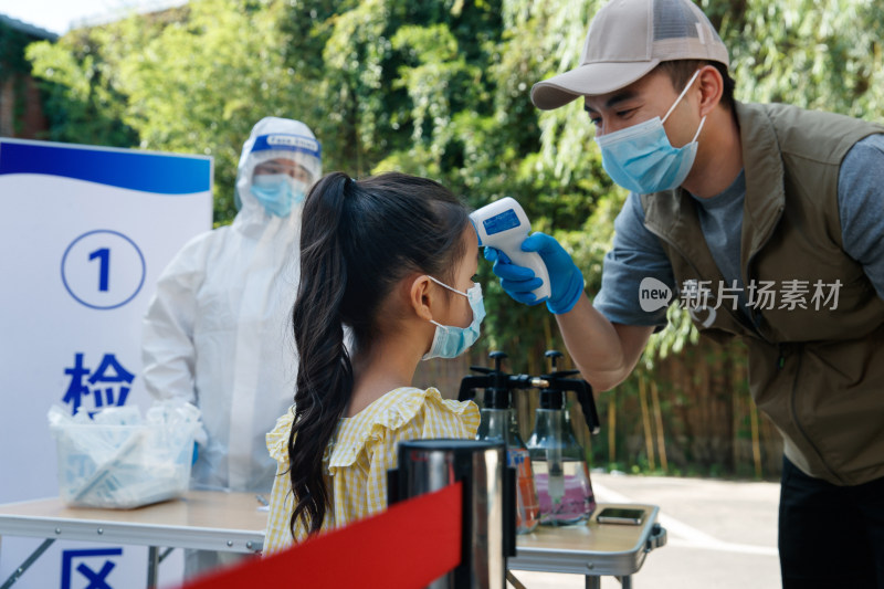 社区志愿者给小女孩测体温