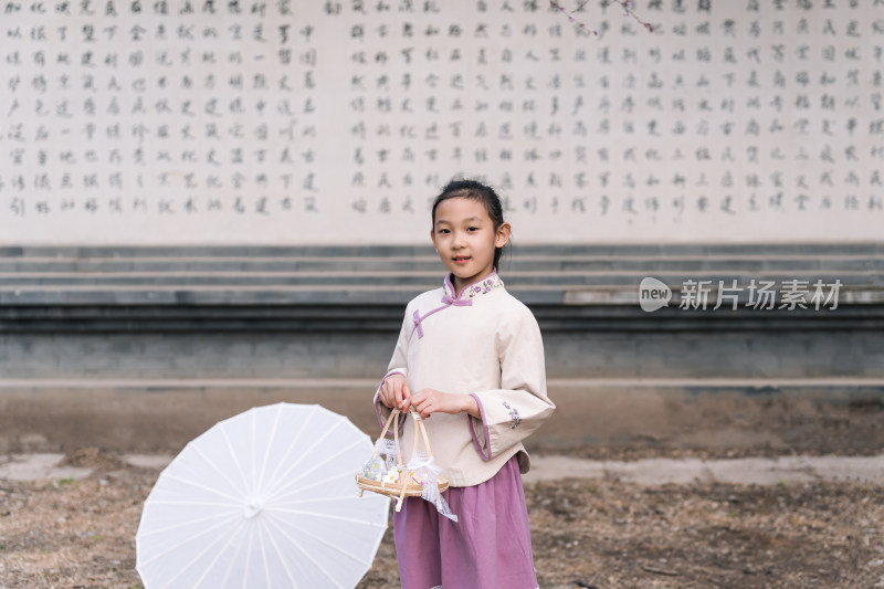 在盛开的桃花树下撑伞的中国女孩