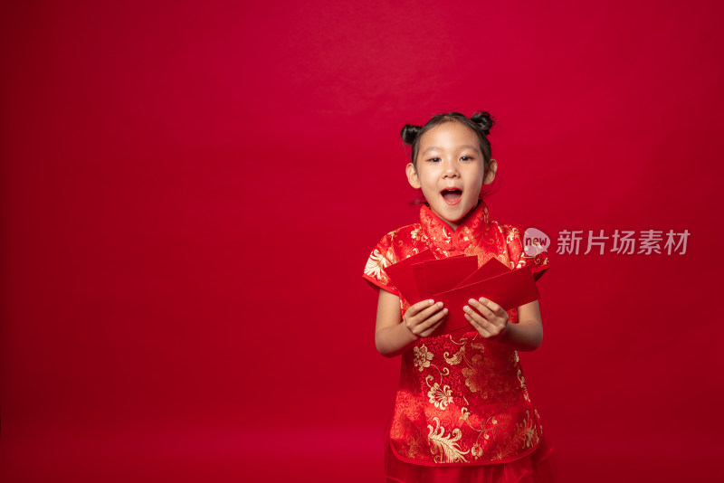 红色背景前穿旗袍拿着多个红包的中国女孩
