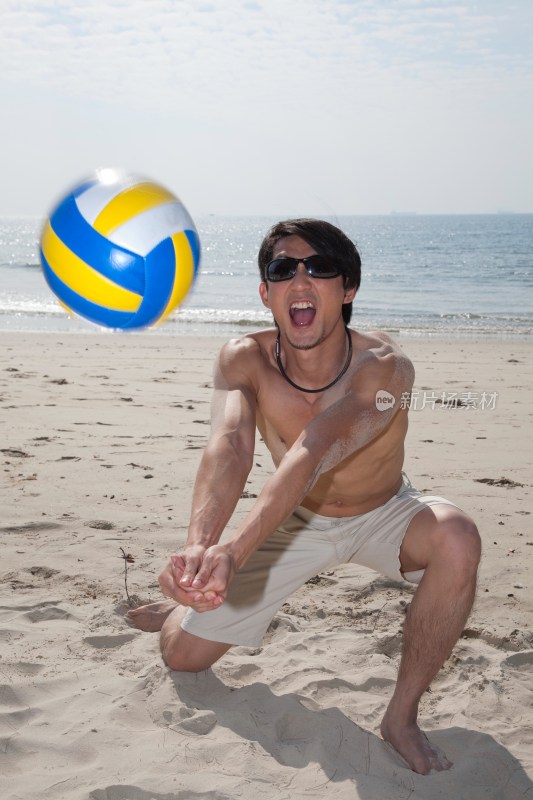 海边年轻男人玩沙滩排球