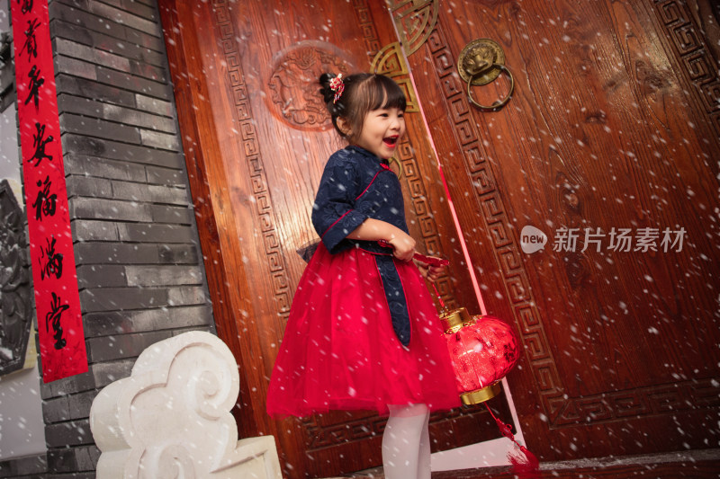 雪中的小女孩手提红灯笼庆祝新年