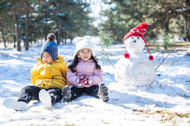 坐在雪地上玩耍的儿童和雪人