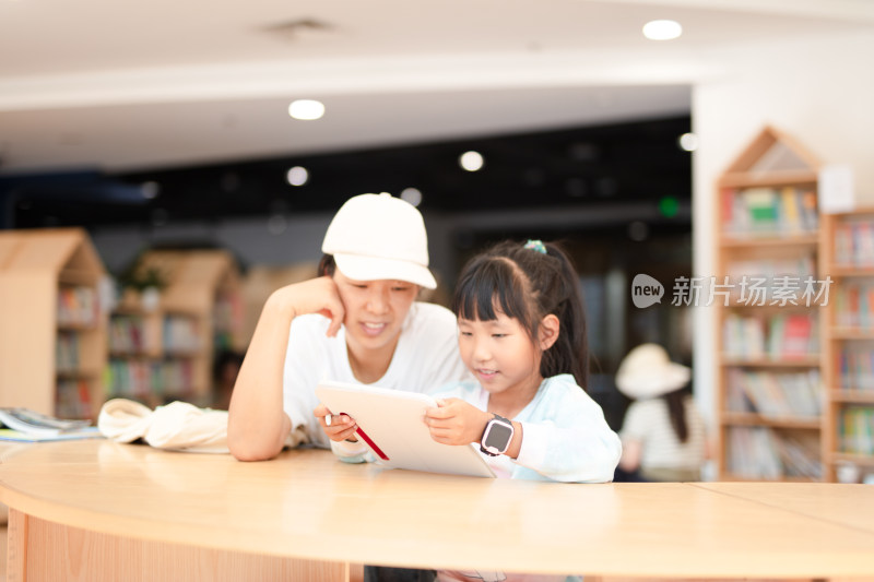 妈妈认真辅导女儿学习在图书馆