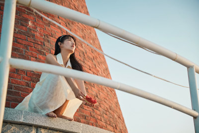 盛夏夕阳湖边码头灯塔上吃西瓜的少女